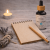 Wellspring, essential oil blend for gentle renewal, bottle beside a pen and notebook, ritual styling, label visible, The Magic Apothecary