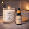 Nightfold candle and oil blend, lit candle scene Nightfold aromatherapy candle and Nightfold essential oil blend bottle on soft fabric, candle lit, wooden lid beside the bottle.